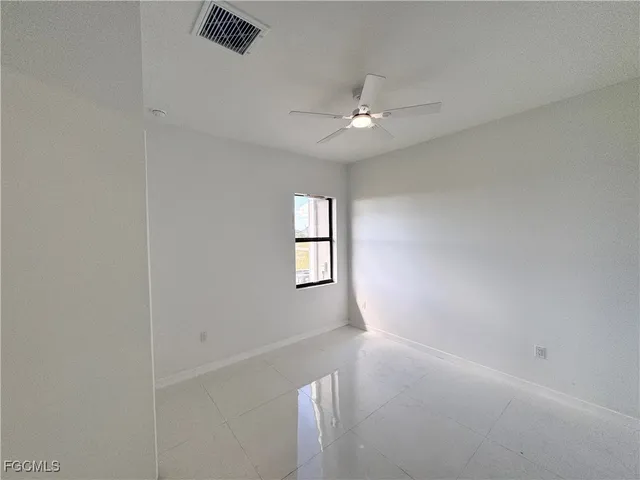 an empty room with windows and fan