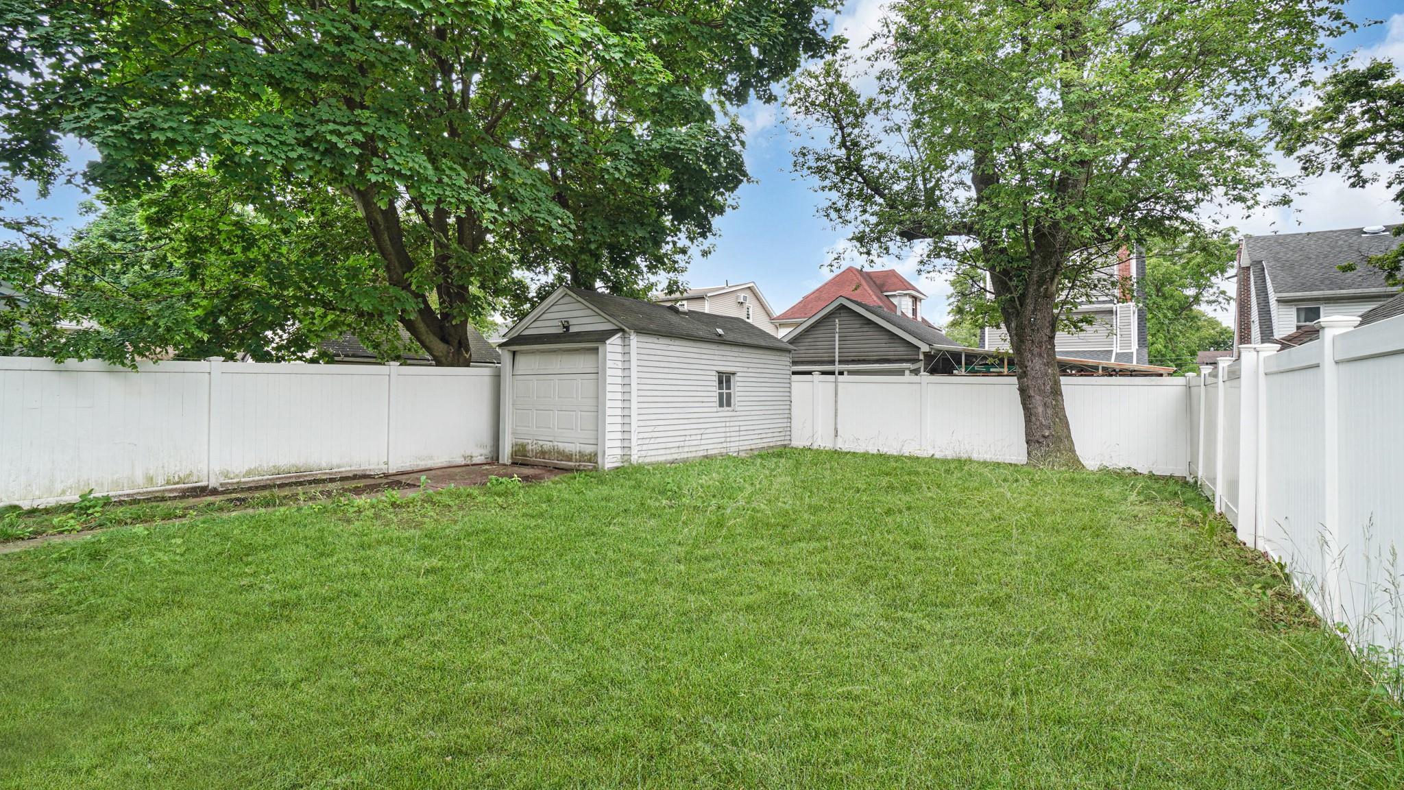 104-28 201st Street Queens, NY 11412 - Photo 11 of 13 Fenced backyard with a detached garage and an outbuilding