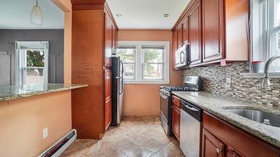 104-28 201st Street Queens, NY 11412 - Photo 4 of 13 Kitchen featuring stainless steel appliances, healthy amount of natural light, backsplash, and brown cabinetry