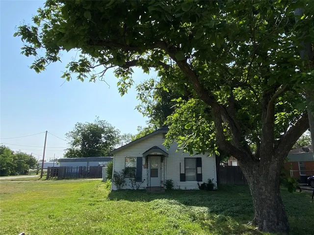 a front view of a house with a garden and tree