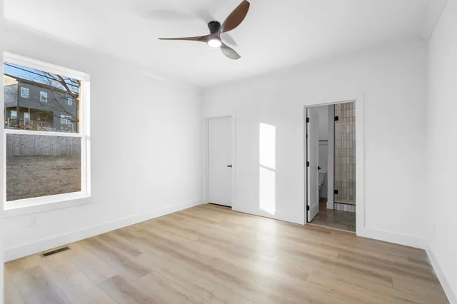 a view of an empty room with a window and wooden floor