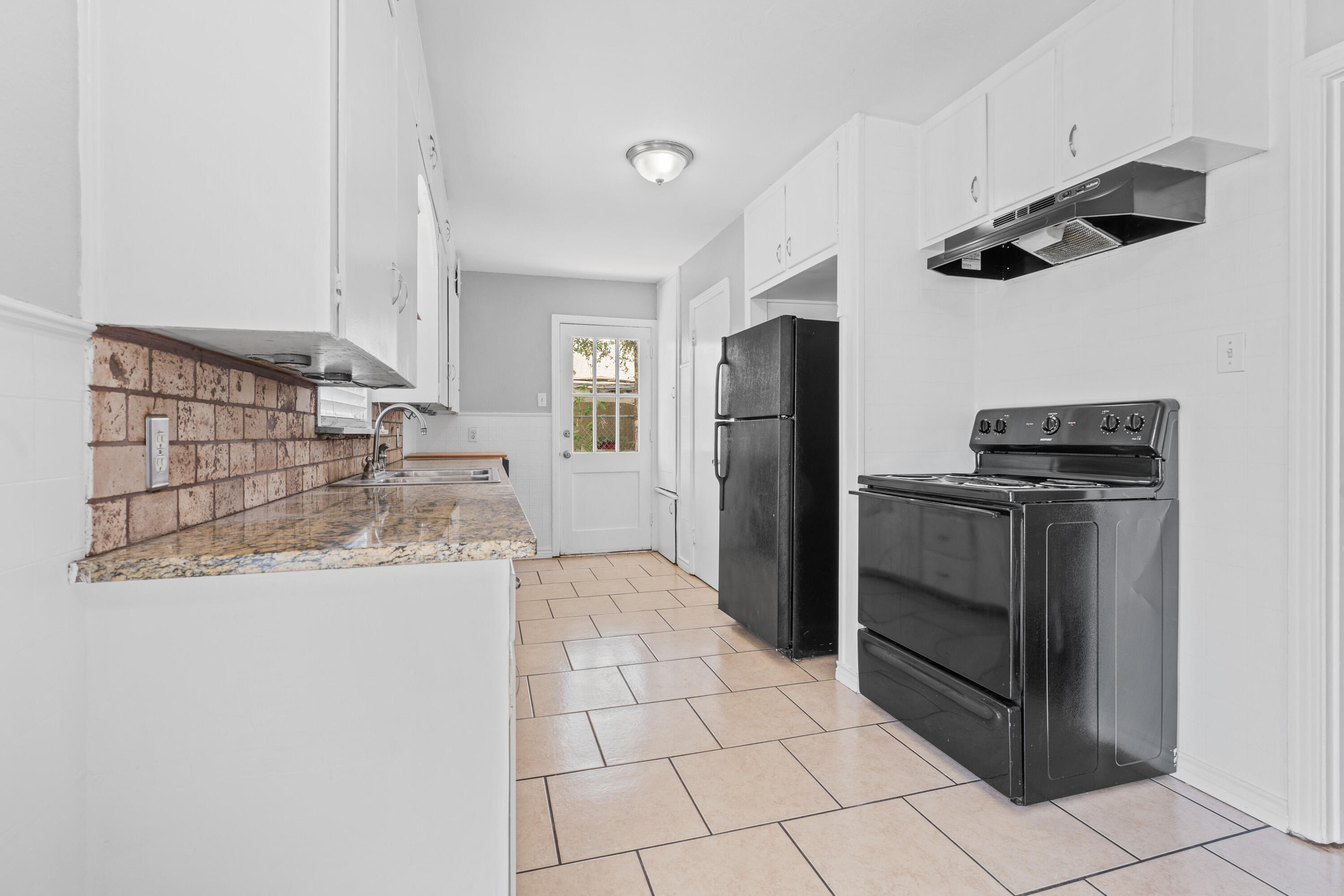 3313 26th Street Lubbock, TX 79410 - Photo 7 of 21 a kitchen with granite countertop a refrigerator and a stove top oven