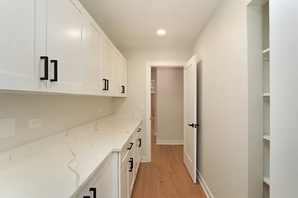 a view of a kitchen with white cabinets and wooden floor