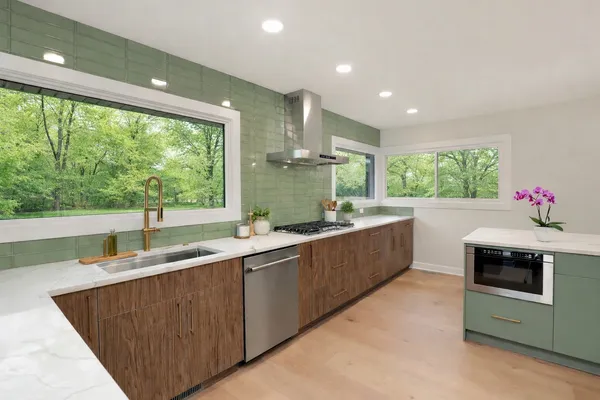a large kitchen with kitchen island a large window in it