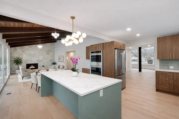 a large kitchen with kitchen island a refrigerator a stove a sink dishwasher and white cabinets with wooden floor