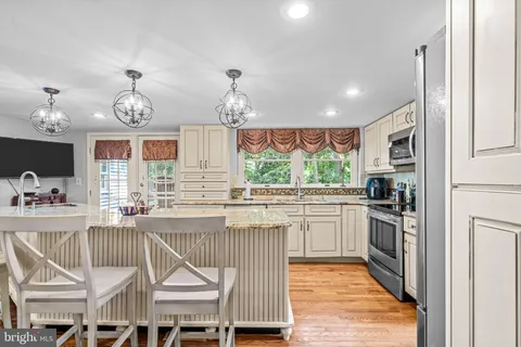 a kitchen with stainless steel appliances granite countertop a stove top oven a sink a dining table and chairs