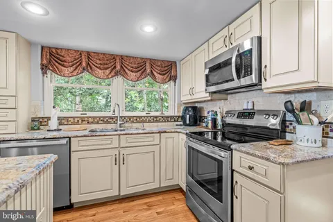a kitchen with stainless steel appliances granite countertop white cabinets a sink and a stove