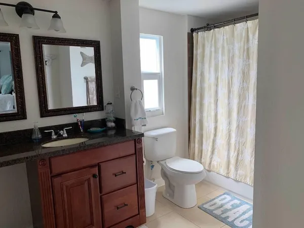 a bathroom with a granite countertop sink toilet and mirror