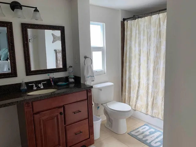 a bathroom with a granite countertop sink toilet and mirror