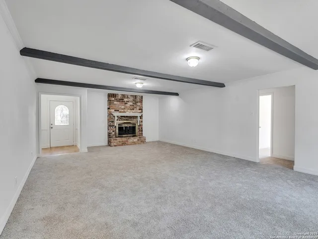 a view of an empty room with a fireplace and a window