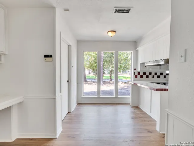 a kitchen with granite countertop a stove top oven a sink and white cabinets with wooden floor