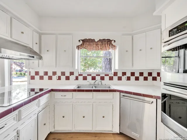a kitchen with granite countertop white cabinets and white appliances