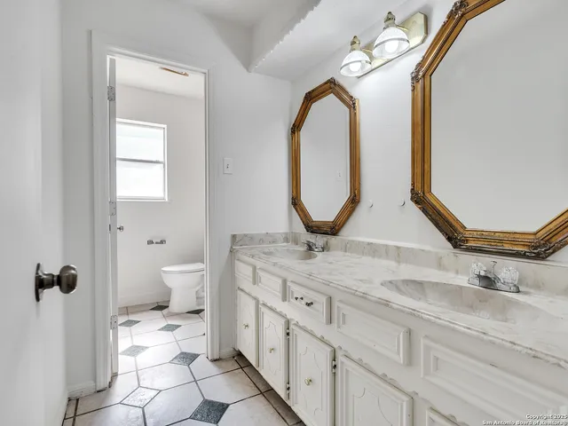 a bathroom with a granite countertop sink a toilet and a mirror