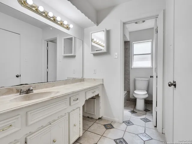 a spacious bathroom with a granite countertop toilet sink and mirror