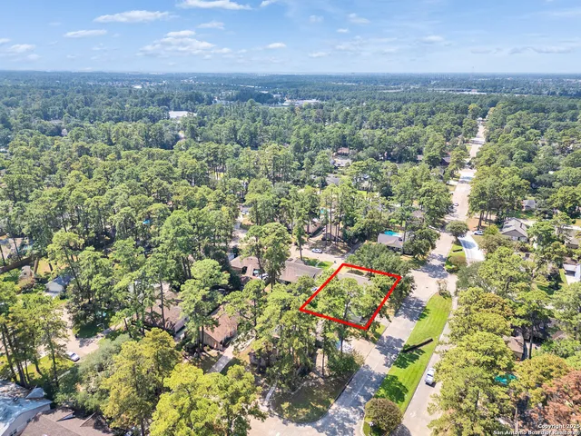 an aerial view of residential houses with outdoor space and trees