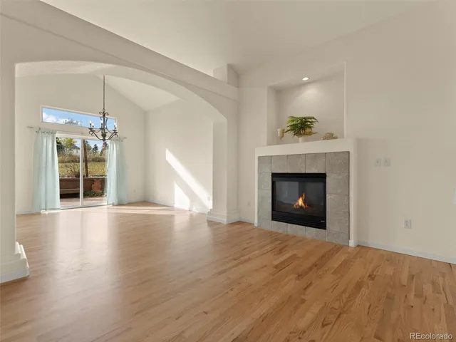 a view of an empty room with wooden floor fireplace and a window