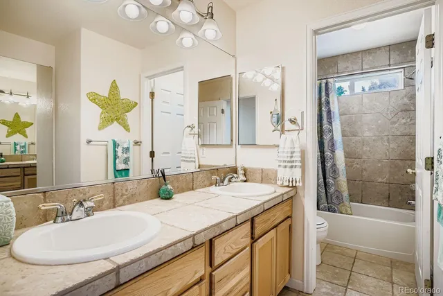 a bathroom with a granite countertop sink a toilet a mirror and shower