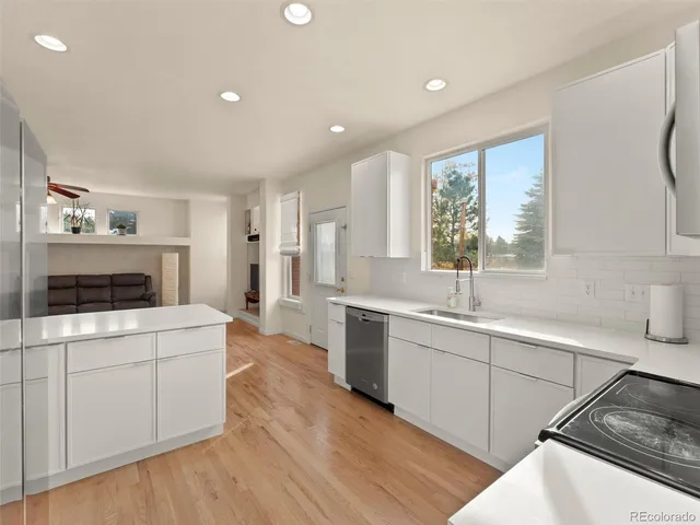 a large kitchen with a stove a sink dishwasher and a refrigerator with wooden floor