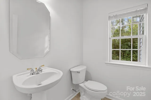 a view of an empty room with wooden floor and a ceiling fan