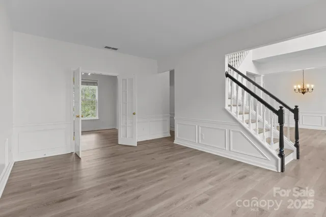 a view of an empty room with wooden floor and a ceiling fan