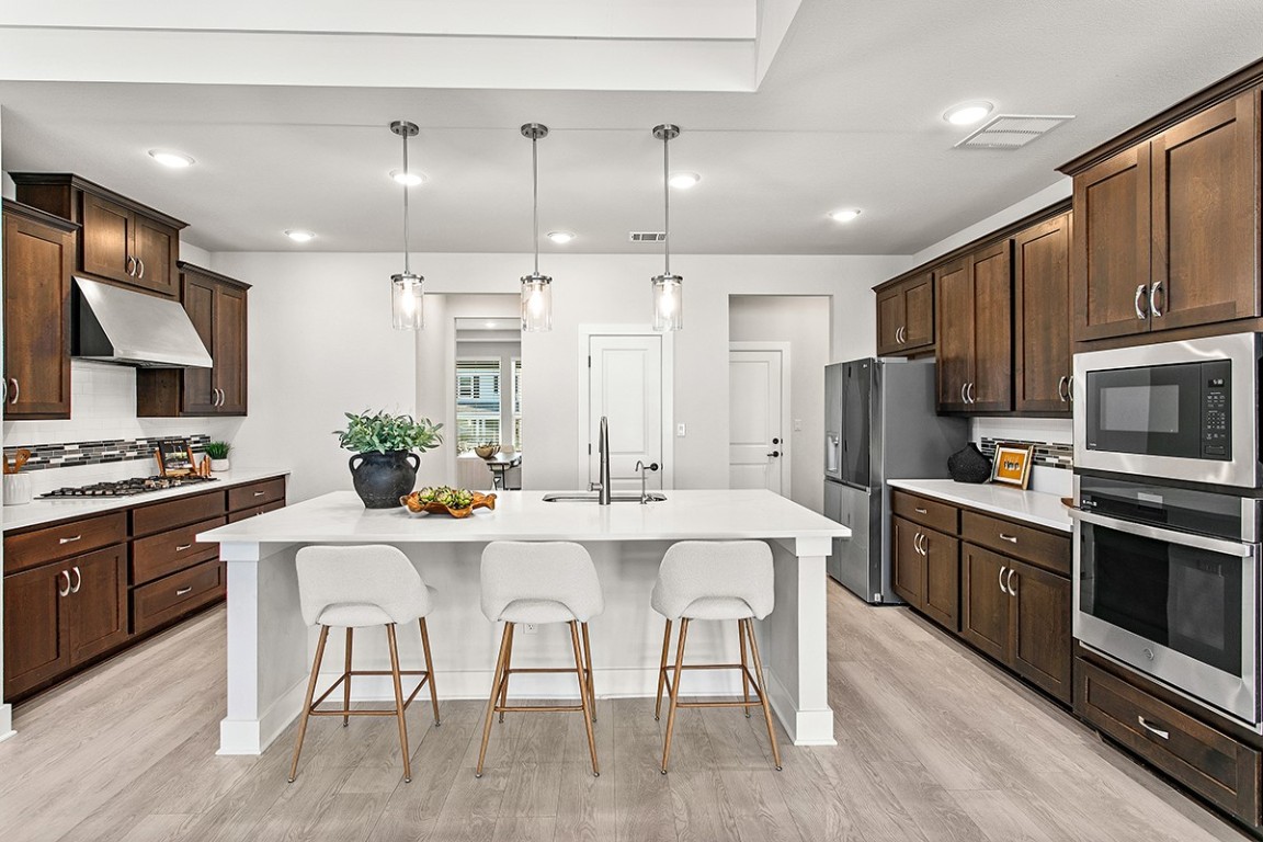 1265 Hazy Hills Loop Dripping Springs, TX 78620 - Photo 6 of 40 a kitchen with stainless steel appliances granite countertop a stove a sink a refrigerator a microwave oven with a dining table and chairs