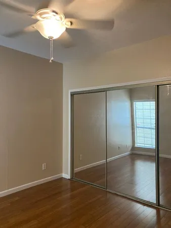 an empty room with wooden floor and fan