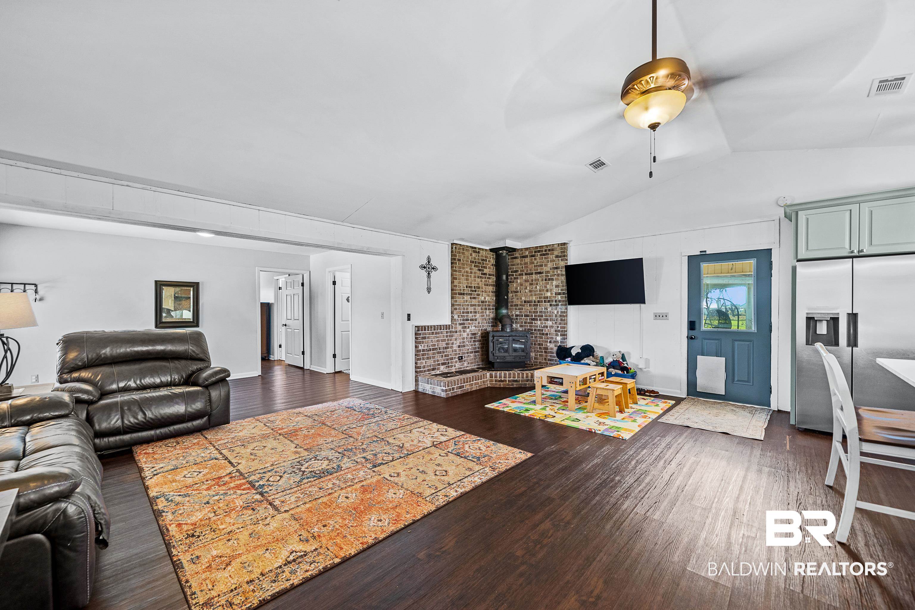 10196 Stucki Road Elberta, AL 36530 - Photo 29 of 54 Living room with a wood stove, vaulted ceiling, dark wood-style flooring, and ceiling fan