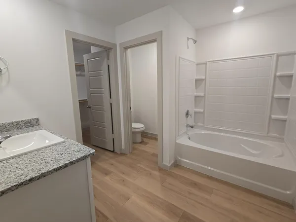 a bathroom with a granite countertop sink a toilet and shower