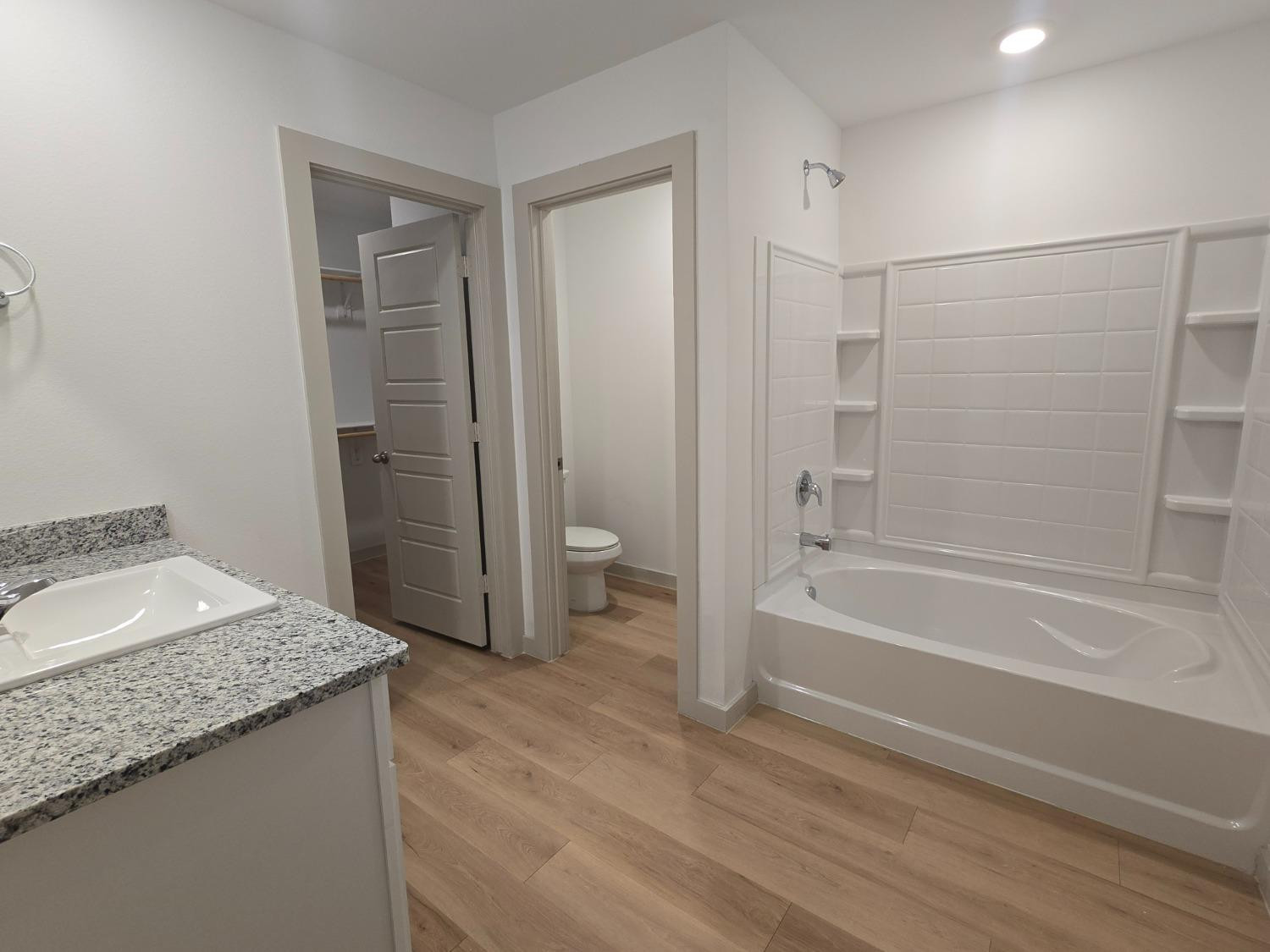 7425 8th Street Lubbock, TX 79416 - Photo 12 of 25 a bathroom with a granite countertop sink a toilet and shower
