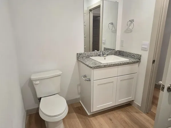 a bathroom with a granite countertop toilet a sink and a mirror