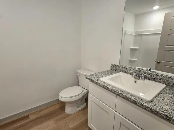 a bathroom with a granite countertop sink and a toilet