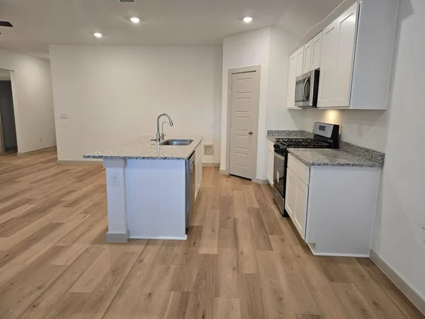 a kitchen with granite countertop a sink stove and cabinets