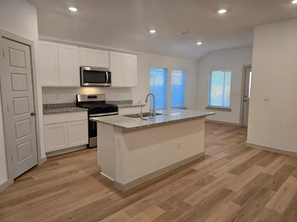 a kitchen with stainless steel appliances granite countertop a stove a sink and a microwave