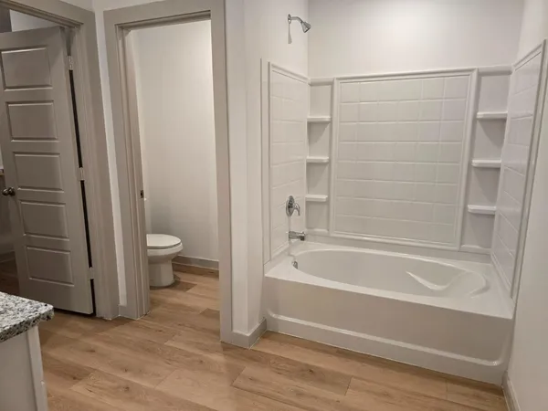 a bathroom with a granite countertop bathtub shower and toilet