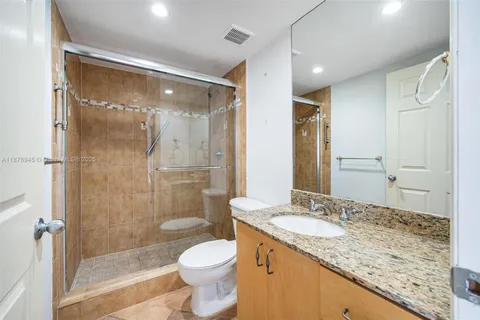 a bathroom with a granite countertop sink toilet and shower glass cabinet