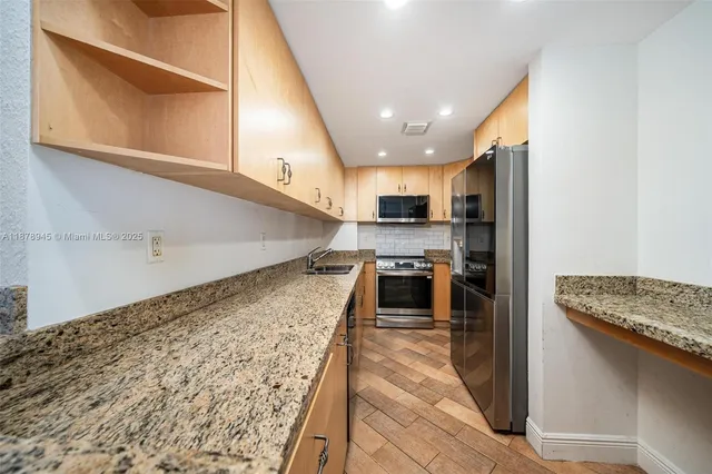 a open kitchen with stainless steel appliances granite countertop a stove a sink and a refrigerator