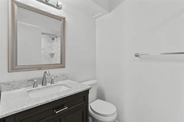 a bathroom with a granite countertop sink a toilet and a mirror