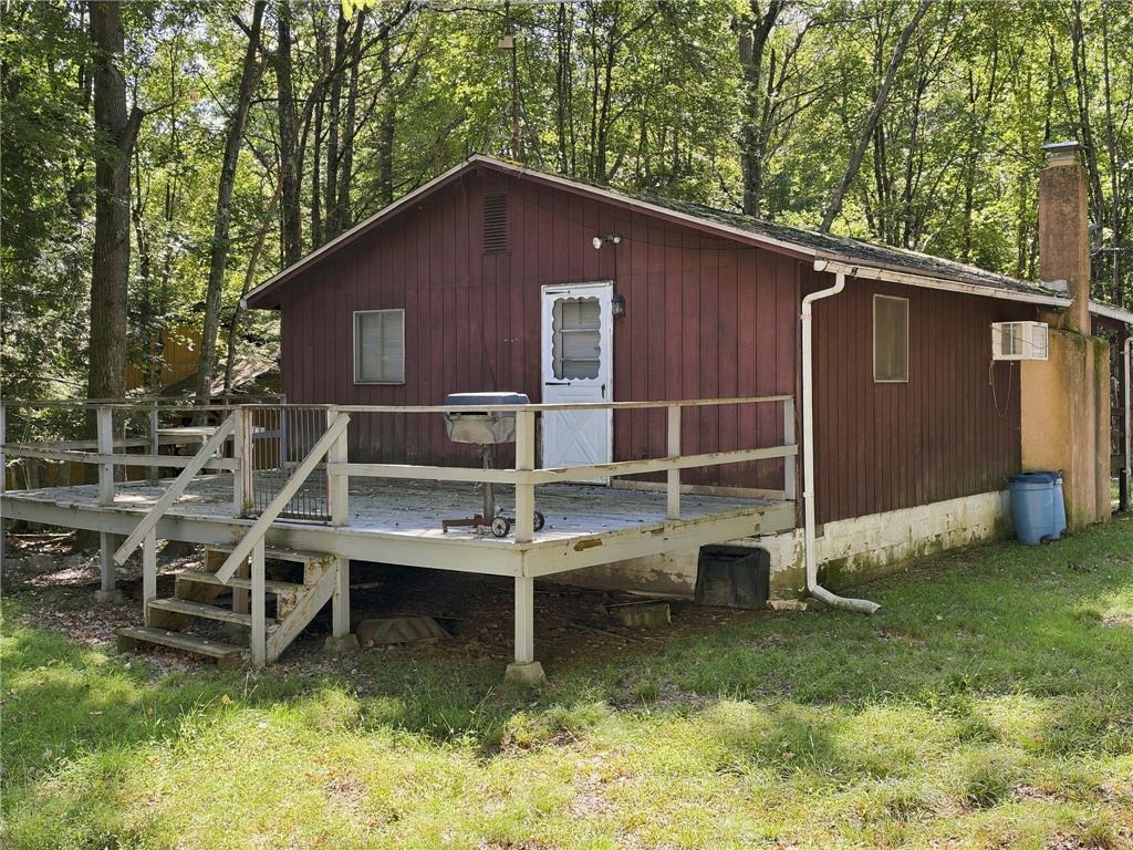 116 Aspen Road Albrightsville, PA 18210 - Photo 6 of 33 Mature trees surround this rustic cabin featuring vertical wood siding and a spacious wooden deck.