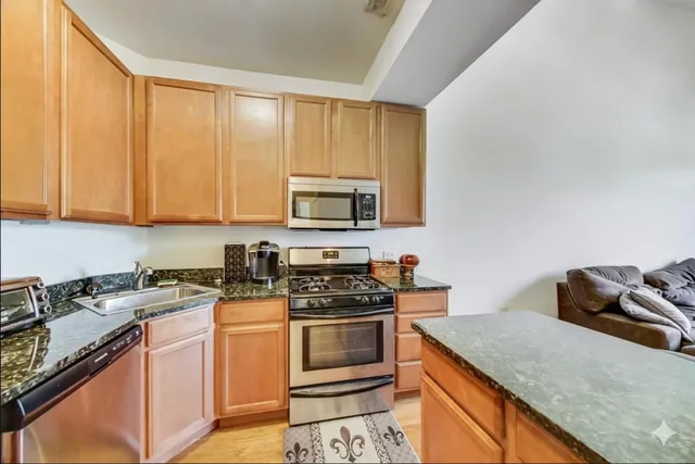 a kitchen with stainless steel appliances granite countertop a stove a sink and a microwave