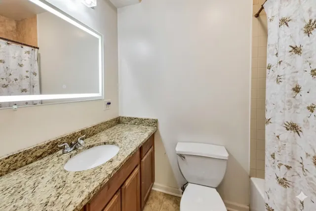 a bathroom with a granite countertop sink toilet and shower