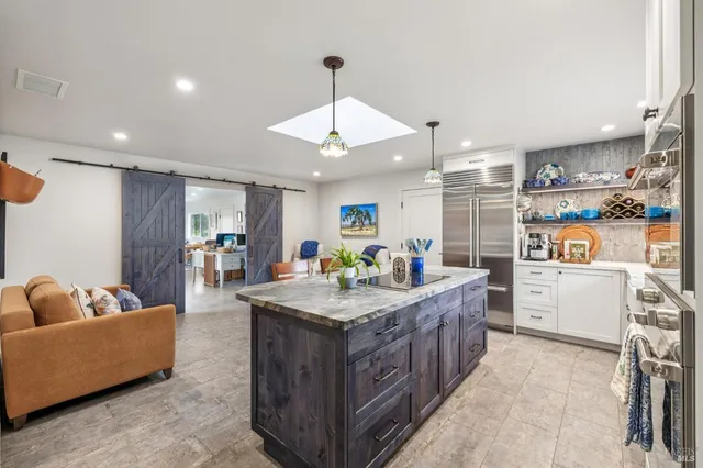 a kitchen with stainless steel appliances kitchen island granite countertop a stove top oven a sink a dining table and chairs with wooden floor