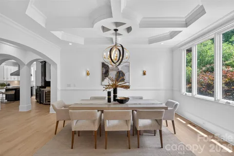 a dining room with wooden floor a chandelier a wooden table and chairs