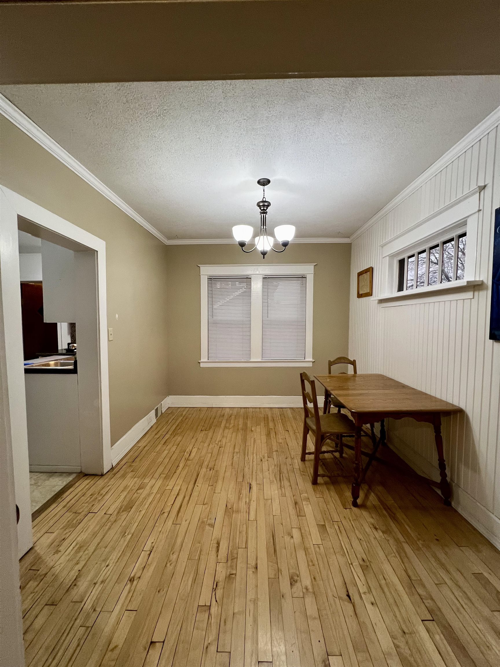 6512 Raleigh Street Duluth, MN 55807 - Photo 3 of 14 Dining space with a chandelier, crown molding, light wood-style floors, and a textured ceiling