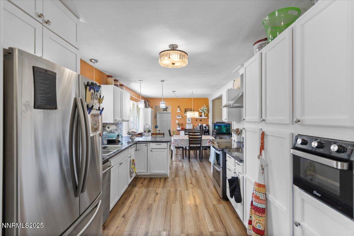 160 Cheyenne Drive Reno, NV 89521 - Photo 4 of 32 a kitchen with stainless steel appliances a refrigerator a stove a microwave oven a sink dishwasher and white cabinets with wooden floor