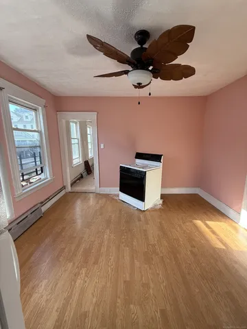 a view of empty room with wooden floor and fan
