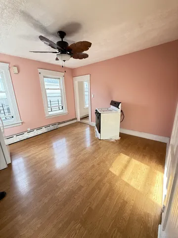 a view of an empty room with window and wooden floor