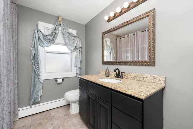 a bathroom with a granite countertop sink a toilet and a mirror
