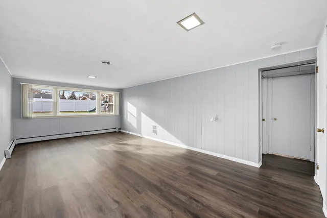 an empty room with wooden floor and window