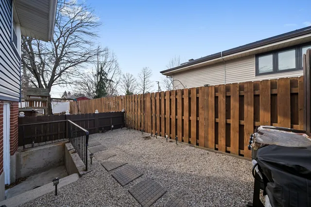a view of a backyard with wooden fence and a barbeque