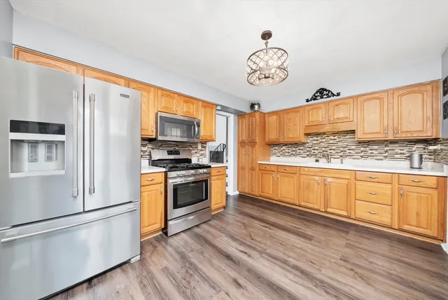 a kitchen with granite countertop stainless steel appliances a stove top oven a refrigerator cabinets and wooden floor